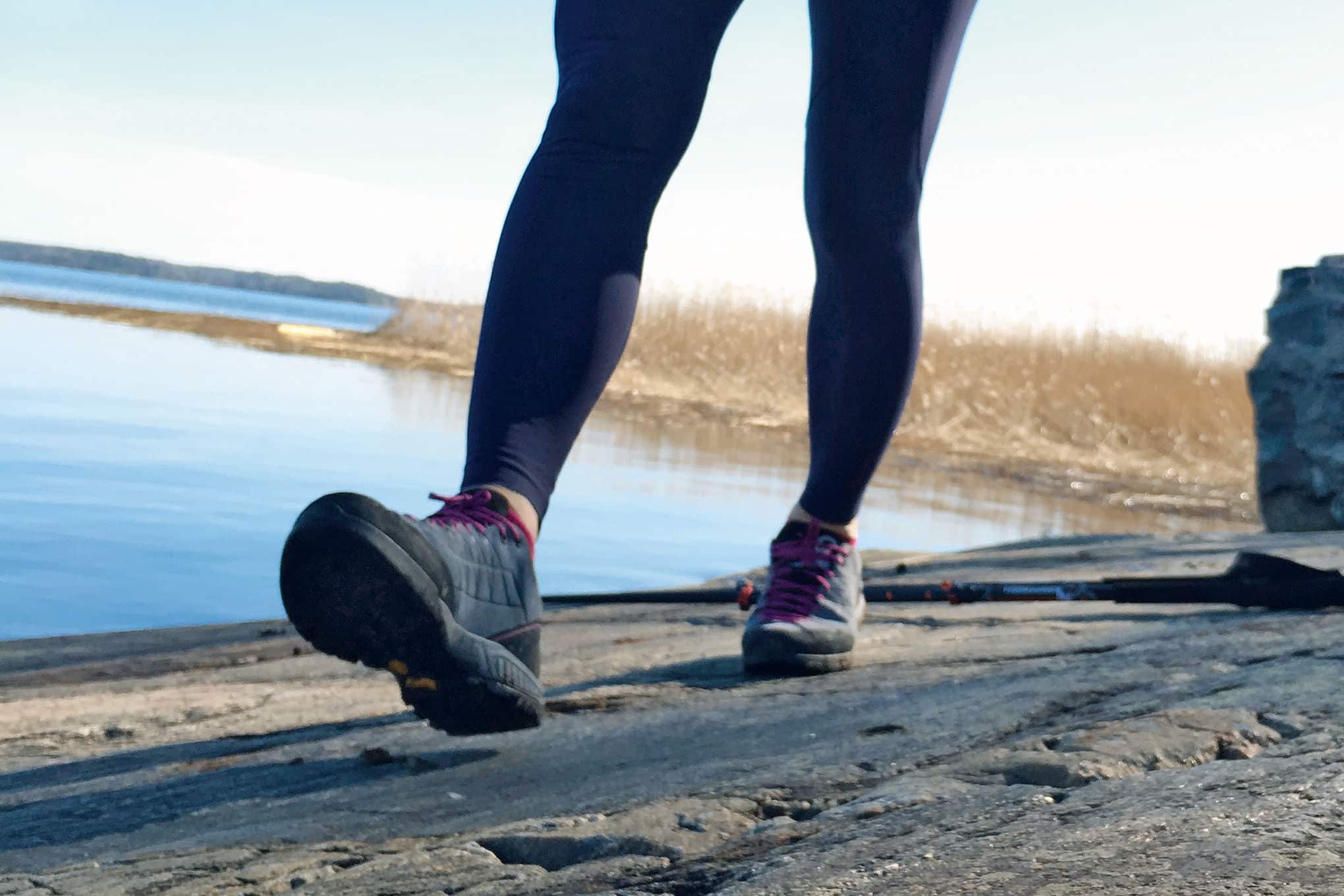 Henkilö kävelemässä kalliolla. Hänellä on jalassaan retkeilykengät.