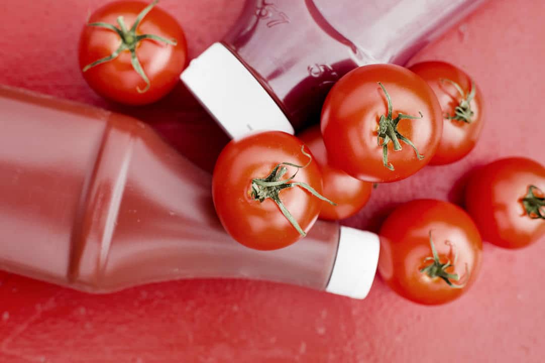 Tomaatteja sekä kaksi ketsuppipulloa.