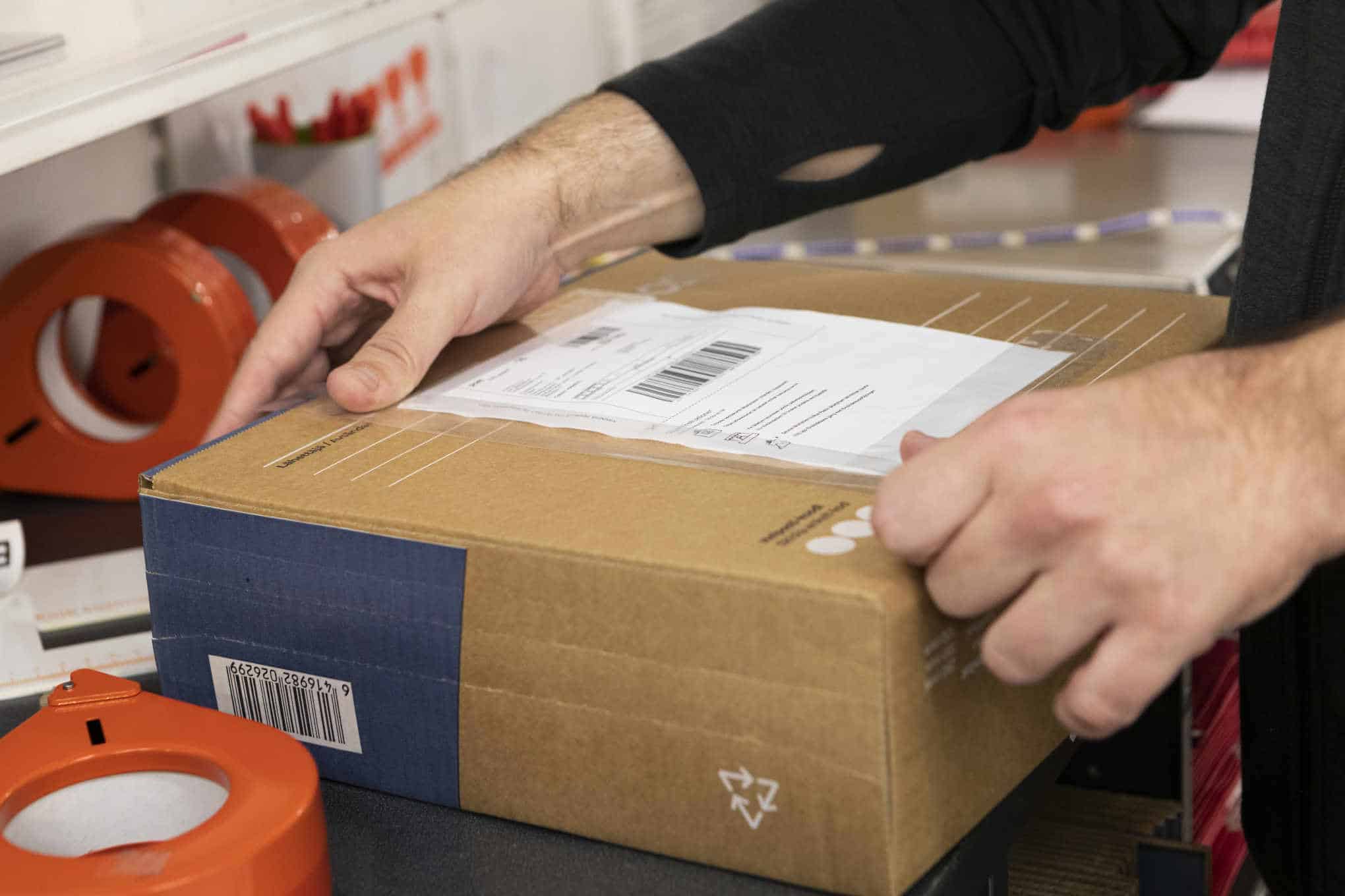 Henkilöllä on käsissään postipaketti.