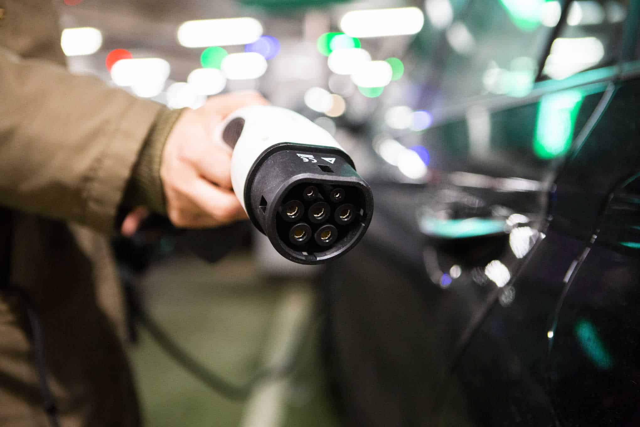 Henkilöllä on kädessään sähköauton latauspistoke.