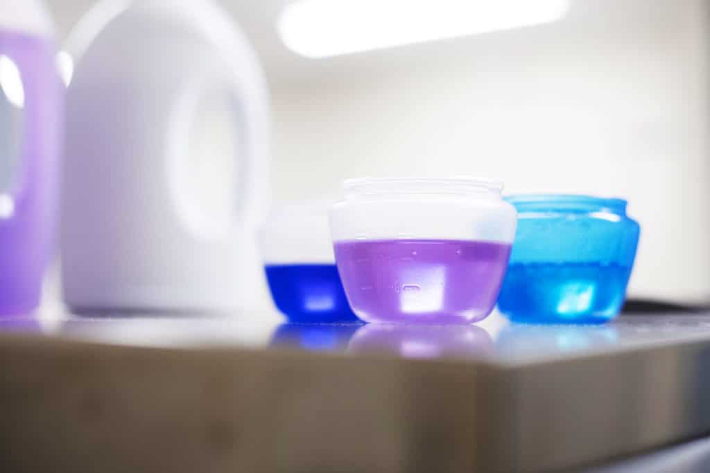 Pyykinpesuainepakkaus ja pesupalloja, joissa on pyykinpesuainetta.