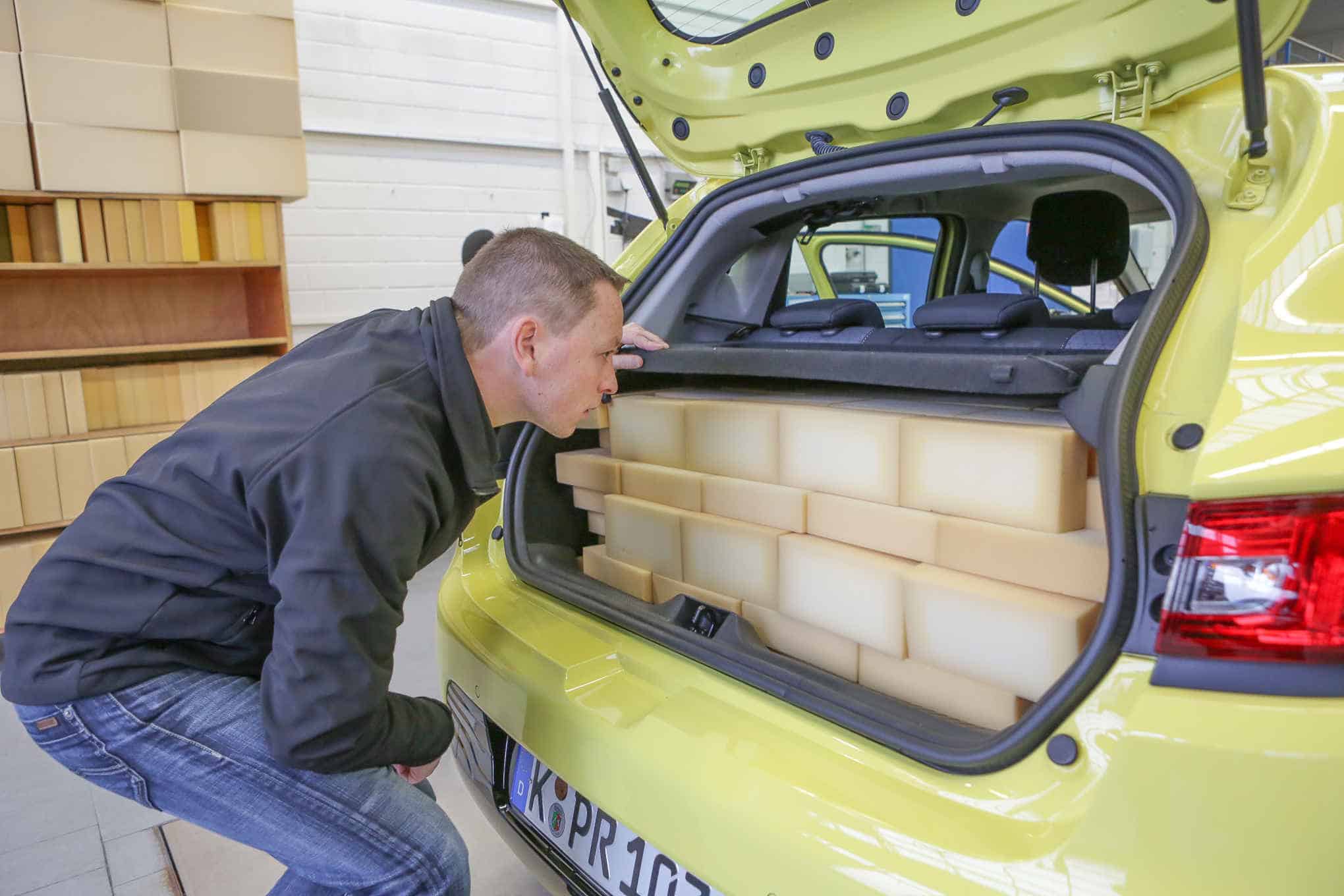 Henkilö tarkastelemassa auton tavaratilassa olevia paketteja.