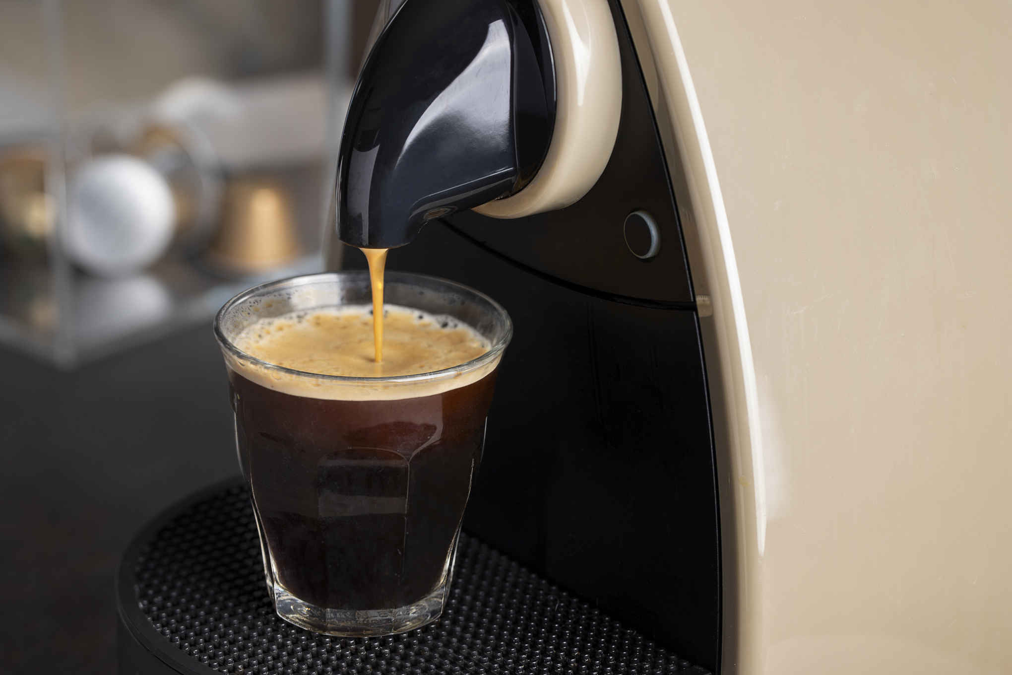 Kapselikahvikone valmistamassa juomaa lasiin.