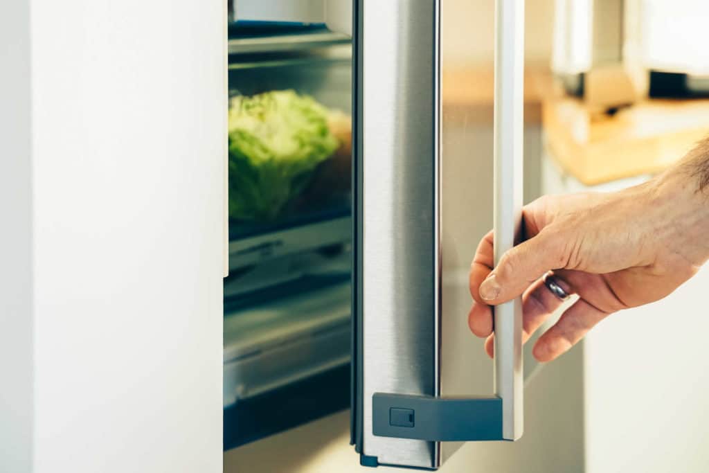 Henkilö avaamassa jääkaappipakastimen ovea.