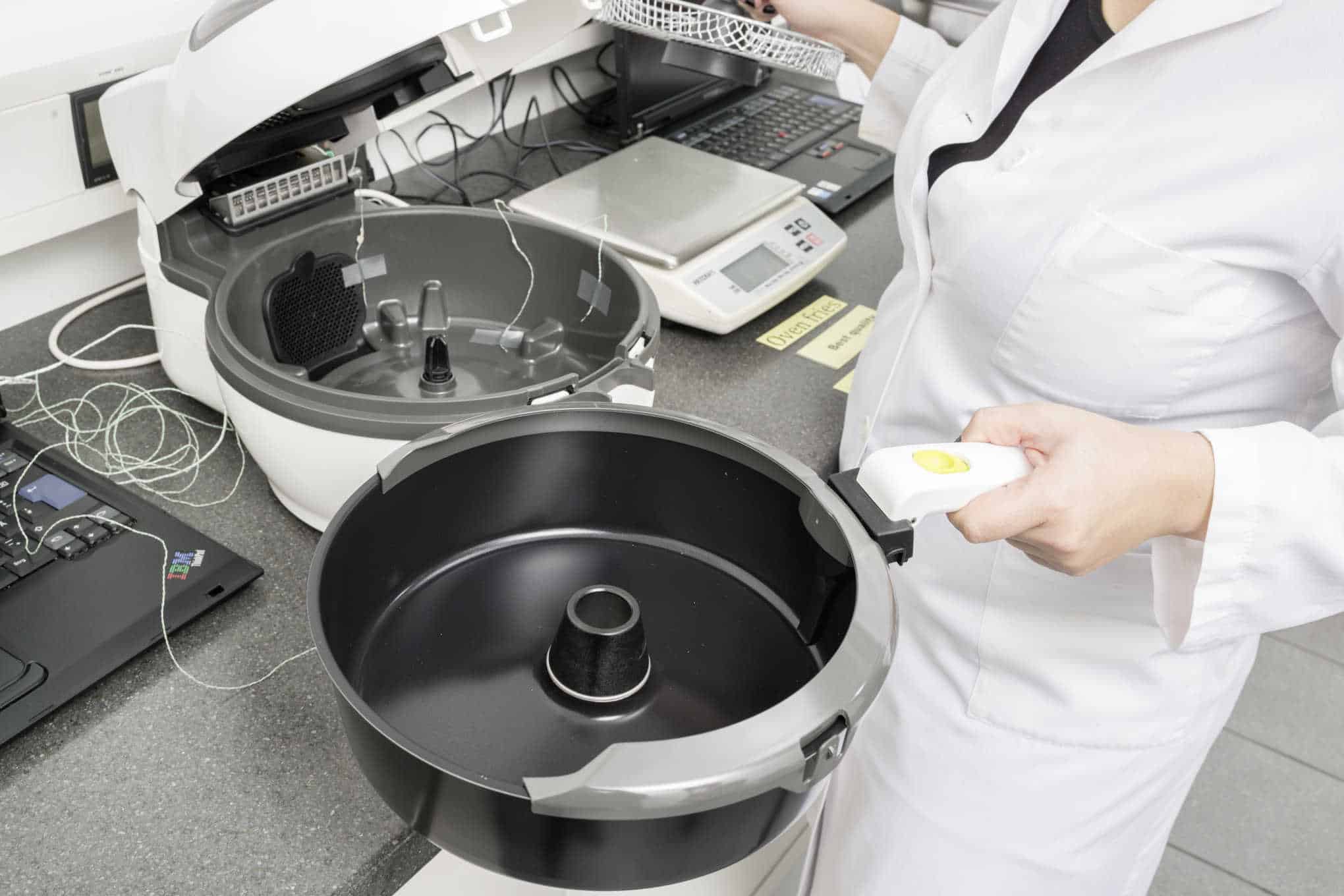 Henkilö käyttämässä airfryerien testauslaitetta laboratoriossa.
