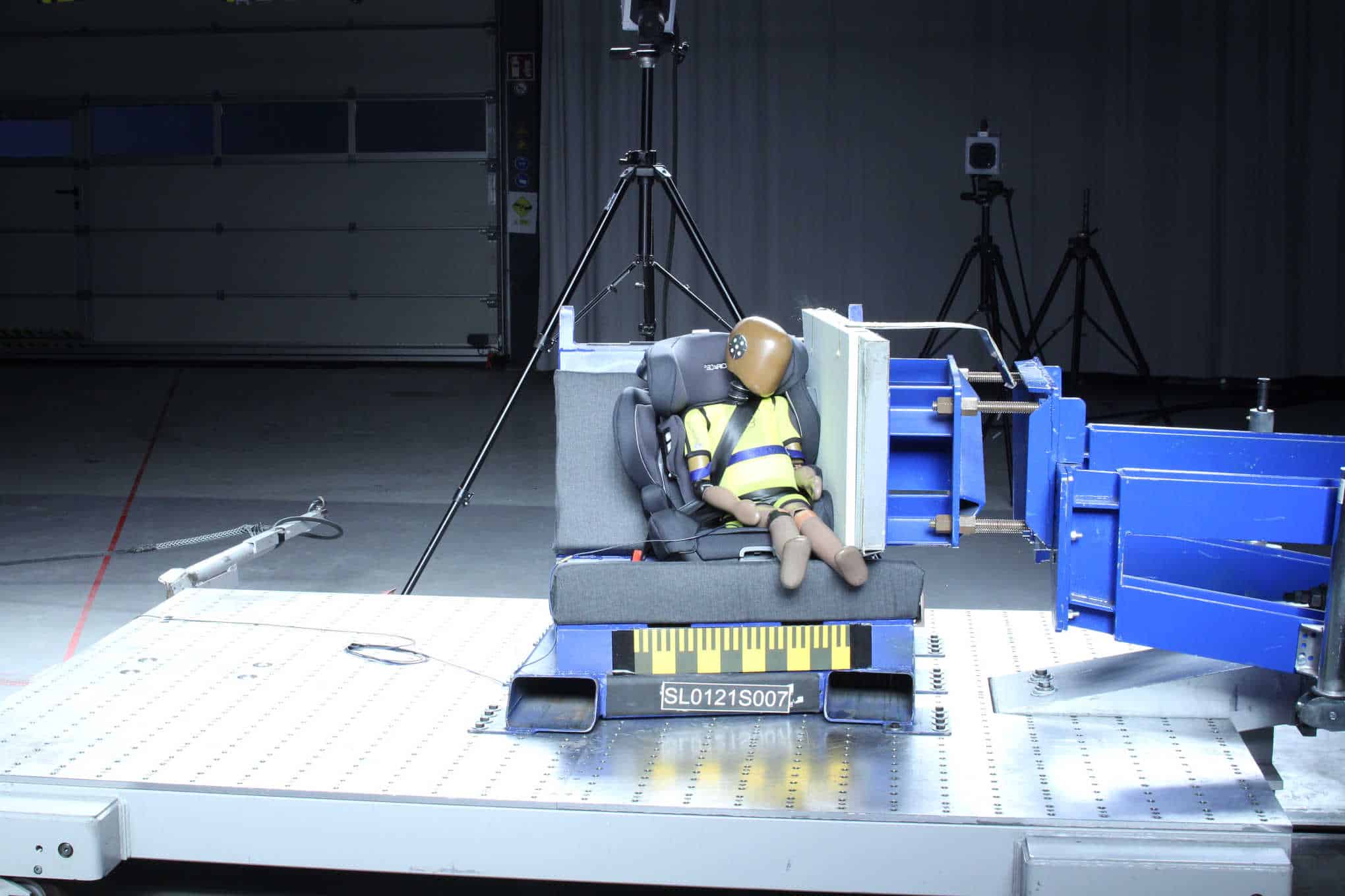 Nukke, joka istuu auton turvaistuimessa sekä testauslaitteistoa.