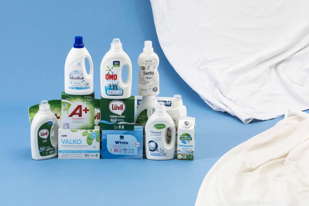 Useiden eri tuotemerkkien valkopesuaineita ja valkoisia kankaita.