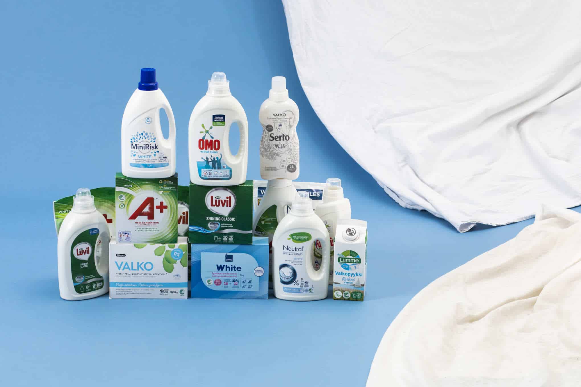 Useiden eri tuotemerkkien valkopesuaineita ja valkoisia kankaita.