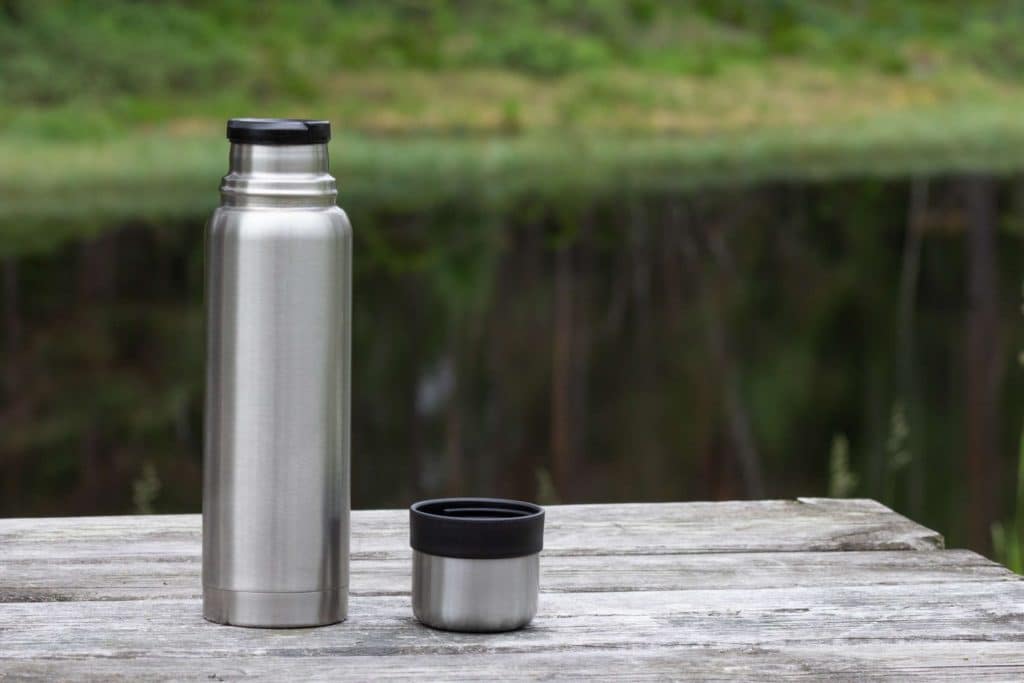 Termospullo puupöydän päällä luonnossa.