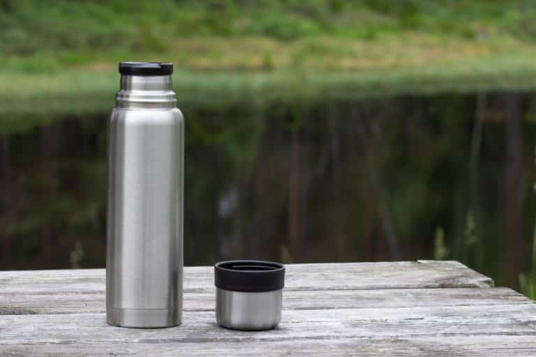 Termospullo puupöydän päällä luonnossa.