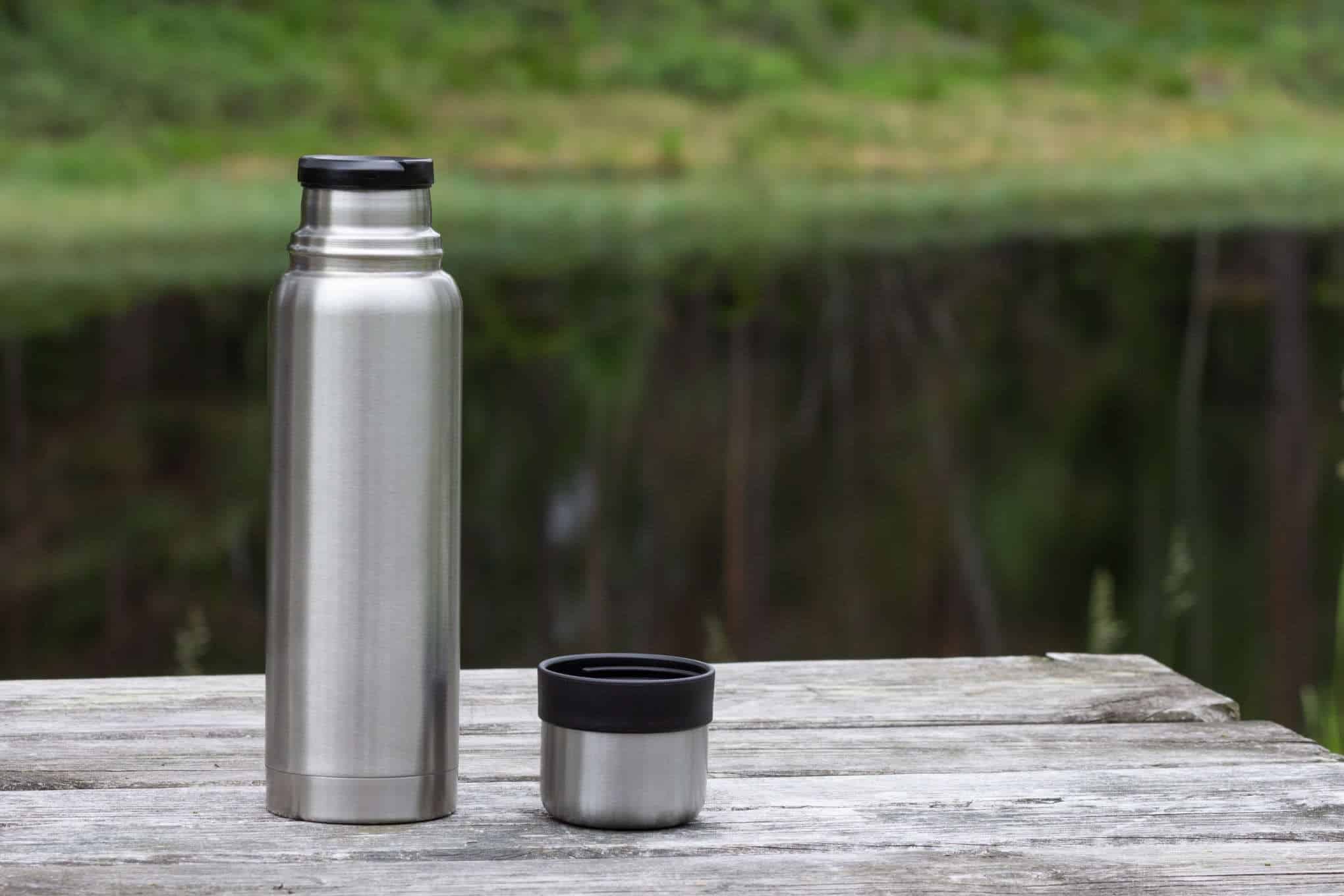 Termospullo puupöydän päällä luonnossa.