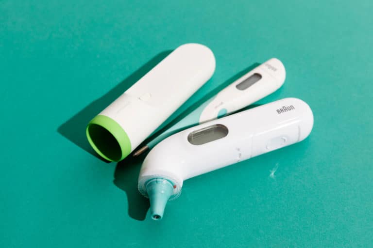 Perinteinen digitaalinen kuumemittari sekä korvaan asetettava kuumemittari.