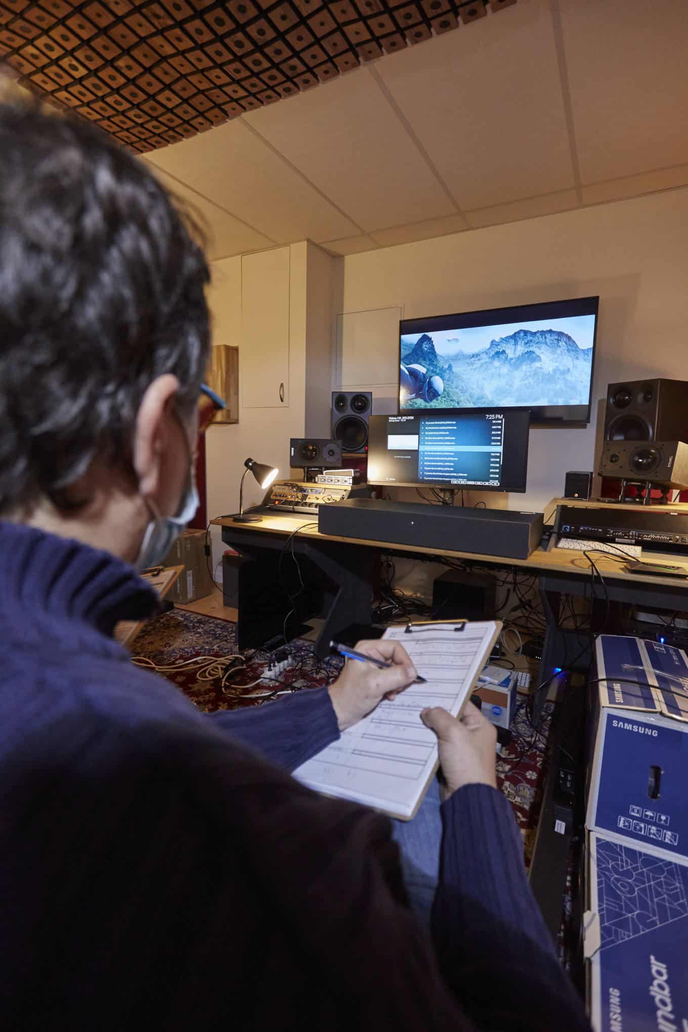 Henkilö istuu huoneessa, jossa on kaiuttimia ja elektroniikkaa.