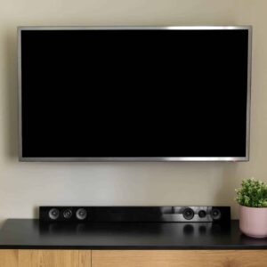 Seinään kiinnitetty televisio ja televisiotaso, jonka päällä on soundbar-kaiutin.