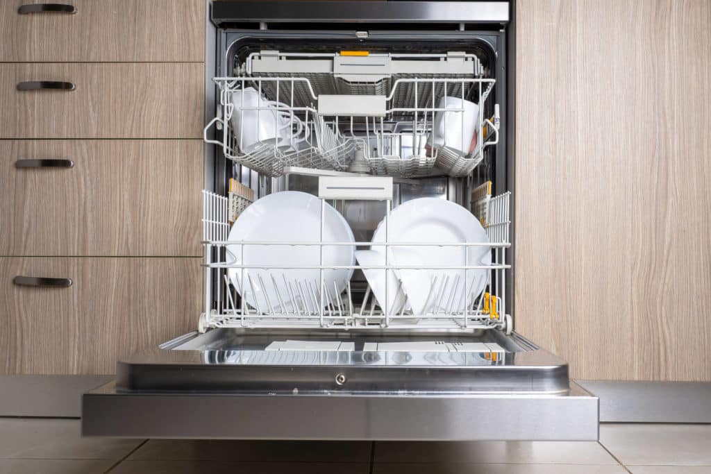 Auki oleva kalustepeitteinen astianpesukone, jonka sisällä on puhtaita astioita.