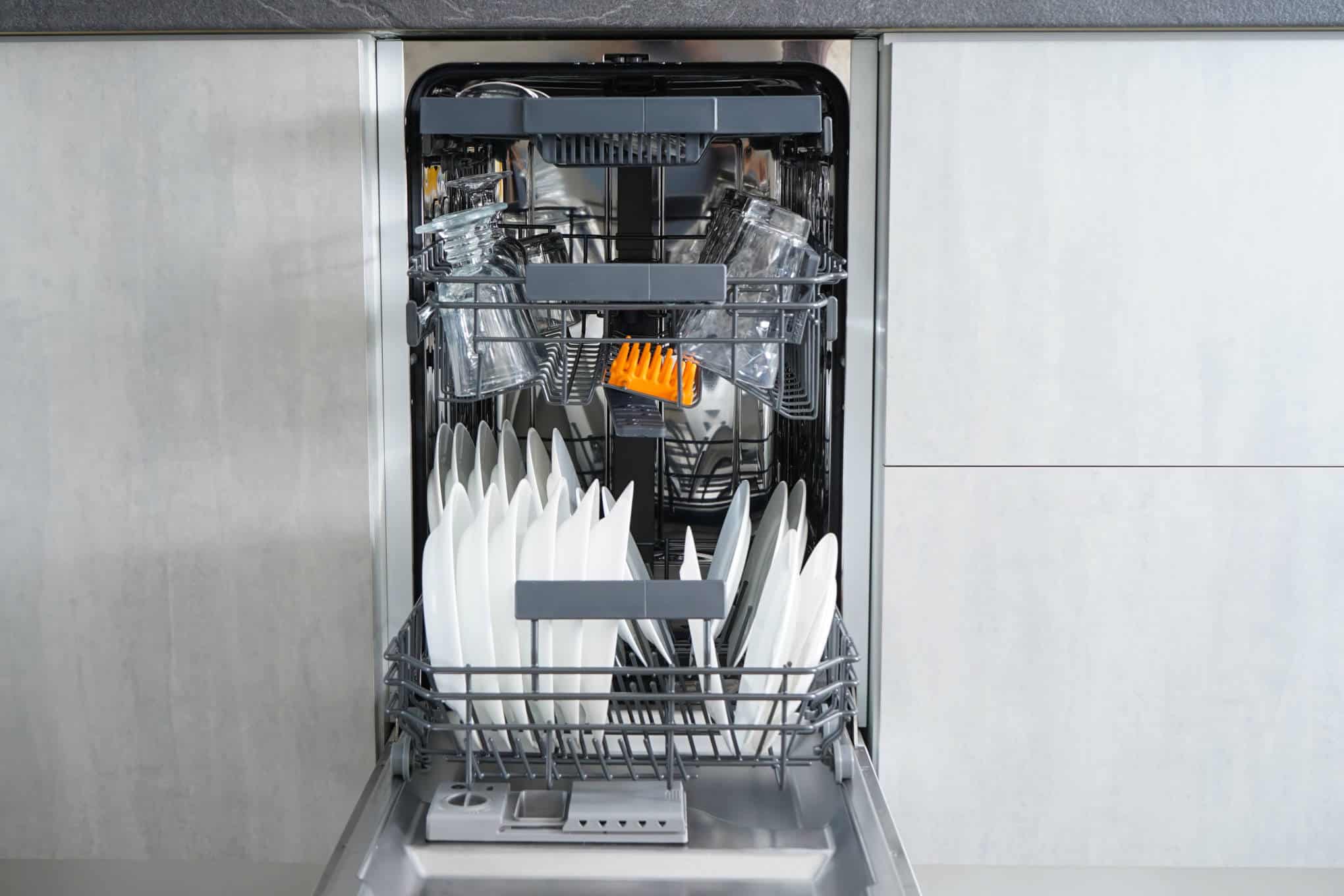 Auki oleva kapea astianpesukone, jonka sisällä on puhtaita astioita.