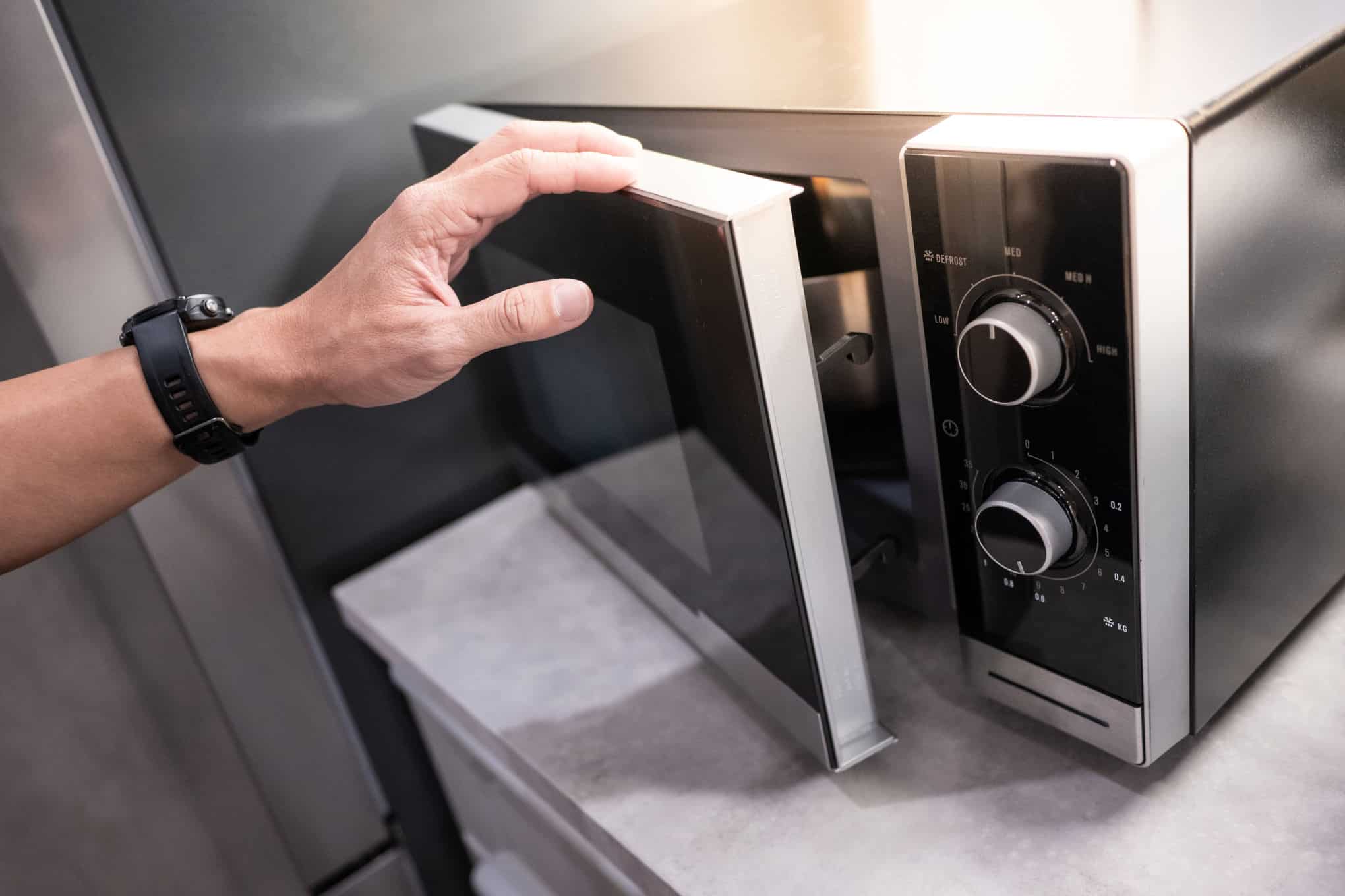 Henkilö avaa mikroaaltouunin ovea.