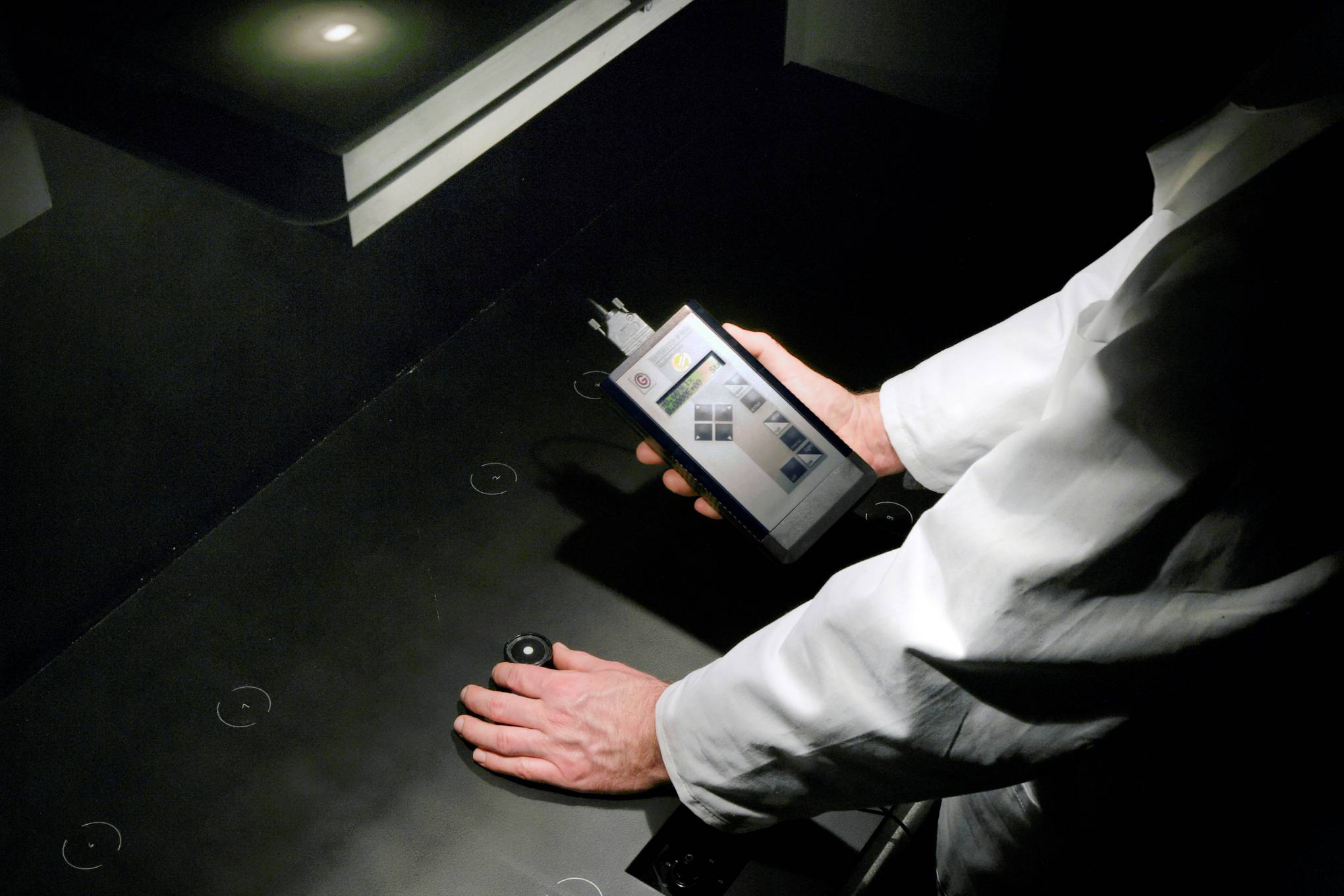 Henkilö, jolla on kädessään valaistuksen mittaukseen tarkoitettu laite.