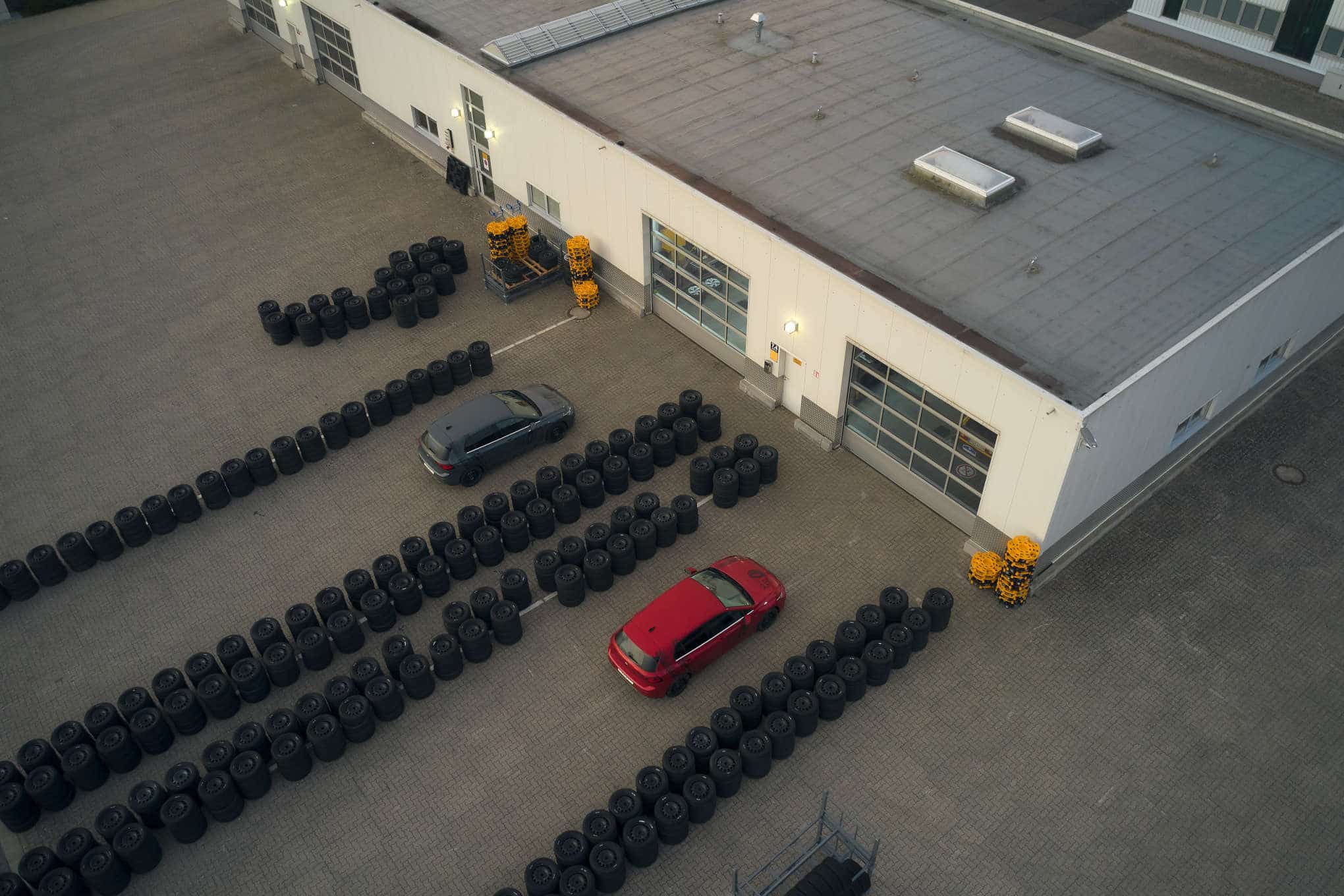 Kaksi autoa ja auton renkaita parkkipaikalla.