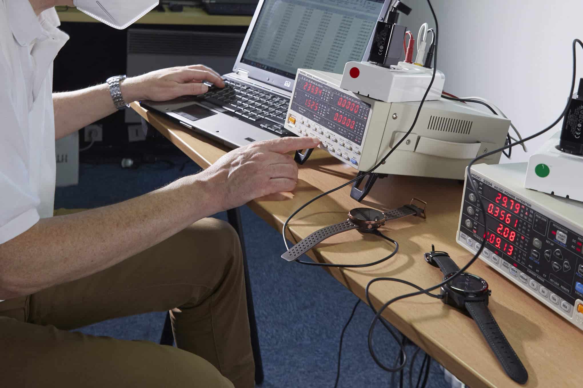 Henkilö testaamassa aktiivisuusrannekkeiden latautumisnopeutta testauslaitteella.