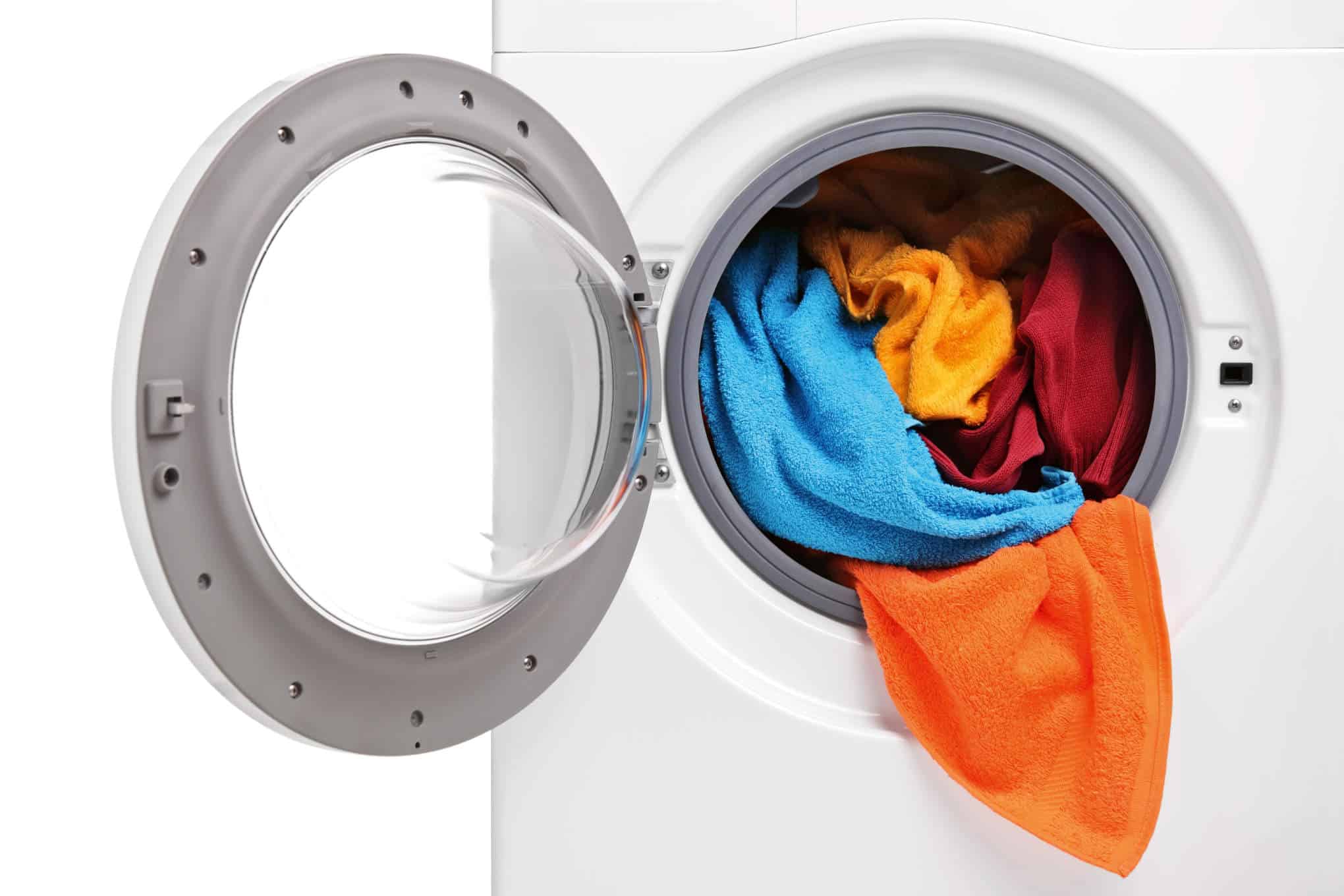 Pesukone, jonka luukku on auki, ja jonka sisällä on värikkäitä tekstiilejä.
