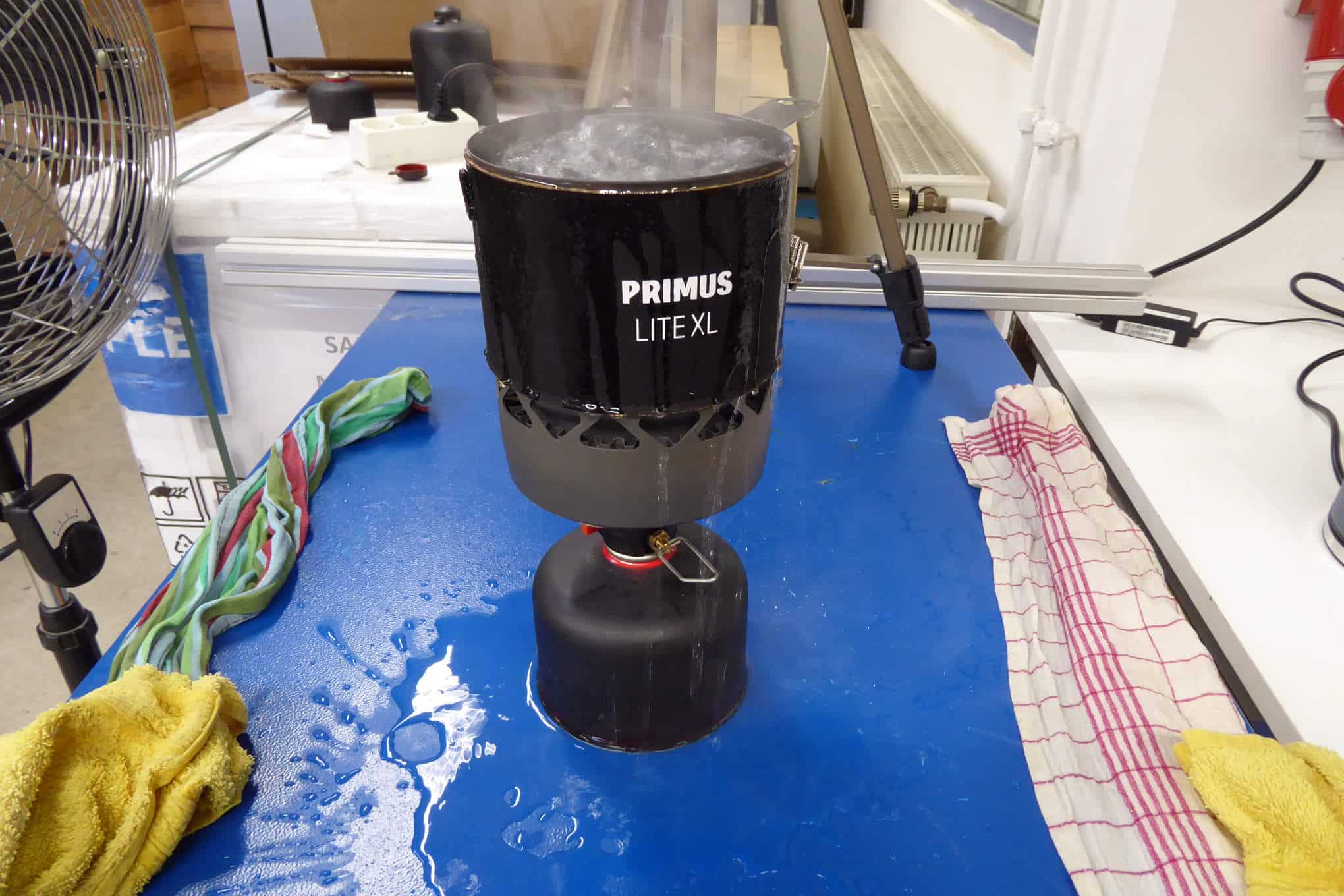 Pöydällä on kaasukeitin, josta kiehuvaksi keitetty vesi roiskuu yli.