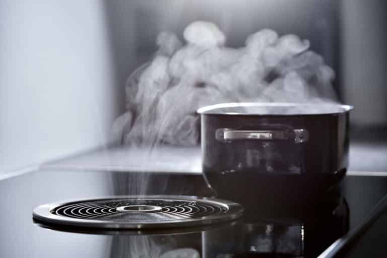Induktiotaso liesituulettimella ja kattila. Liesituuletin imee kattilasta tulevaa höyryä.