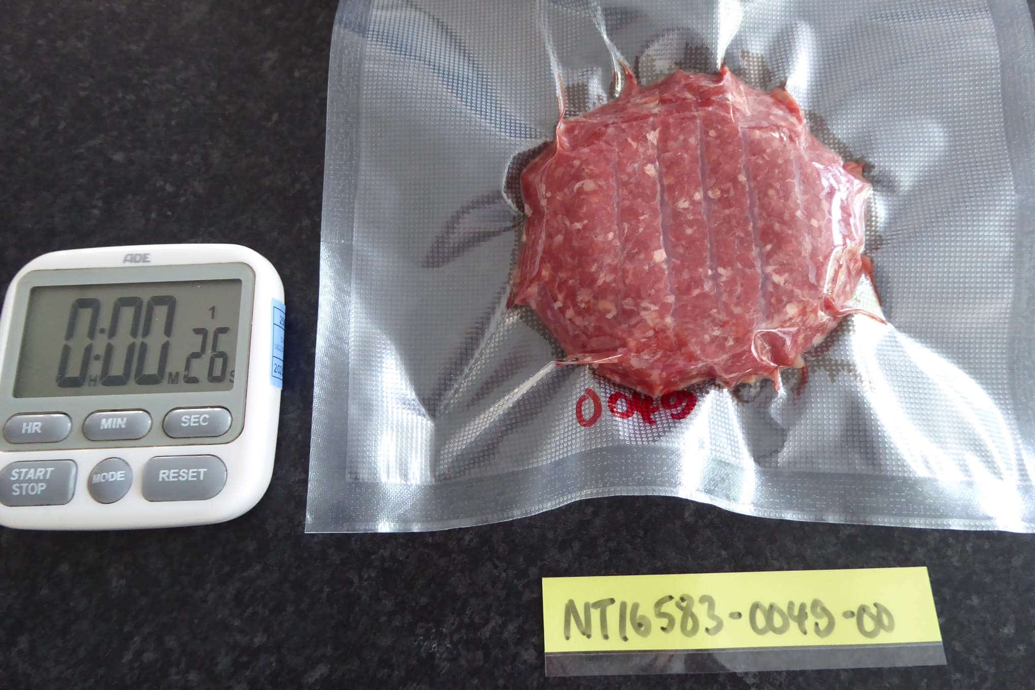 Tyhjiöpakkauslaitteella vakumoitua lihaa ja sekuntikello.