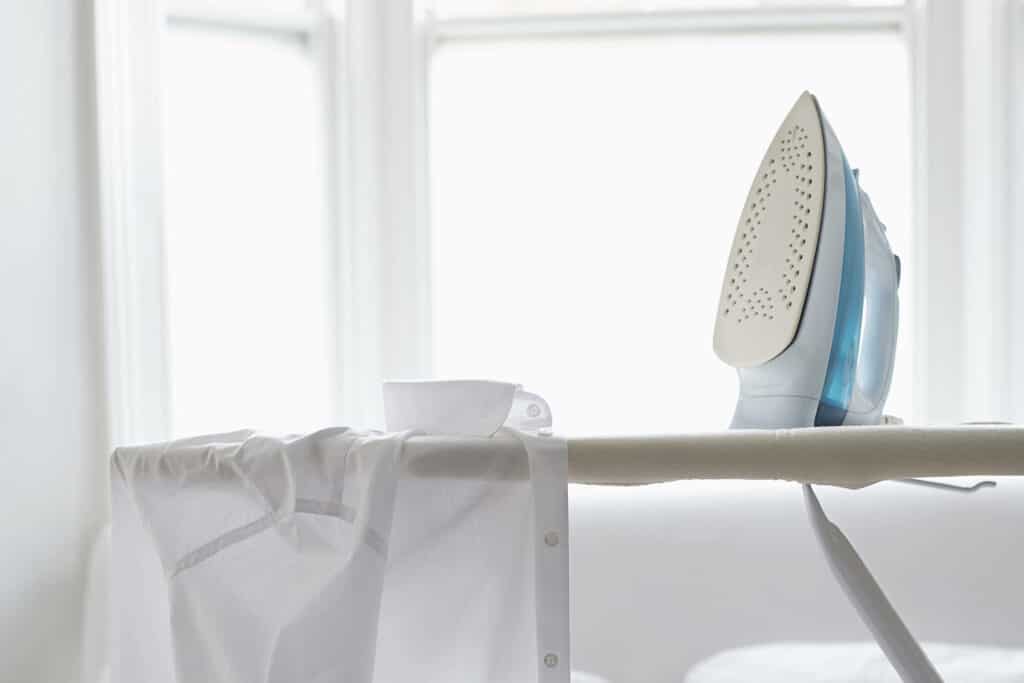 Silityslaudalla on silitysrauta ja valkoinen kauluspaita.