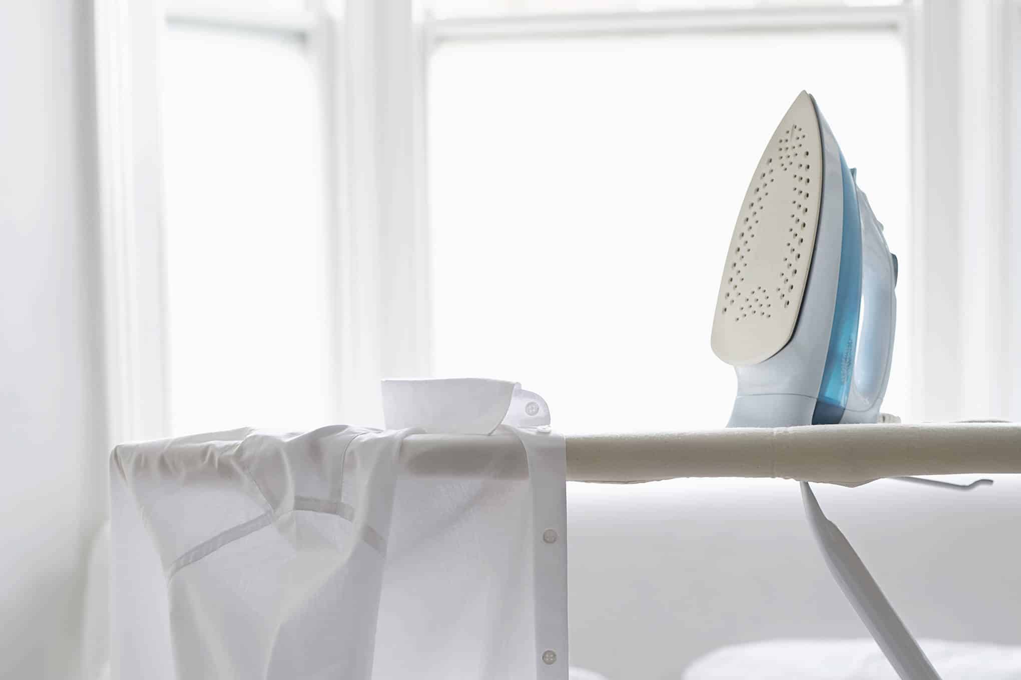 Silityslaudalla on silitysrauta ja valkoinen kauluspaita.