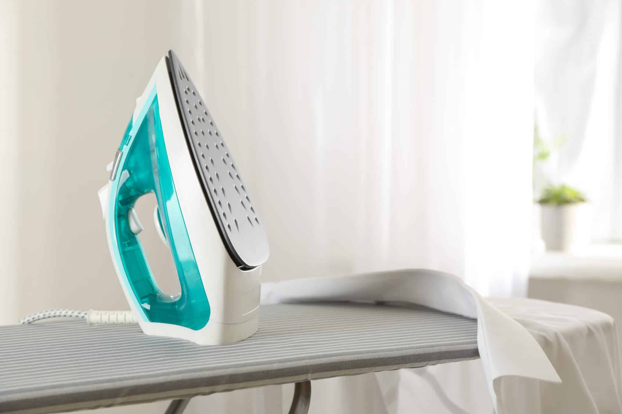 Silityslaudan päällä on silitysrauta ja valkoinen kauluspaita.