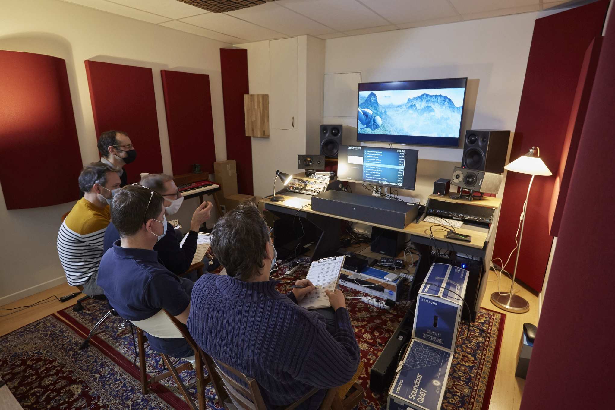Viisi henkilöä istuu huoneessa, jossa on kaiuttimia ja testauslaitteistoa.
