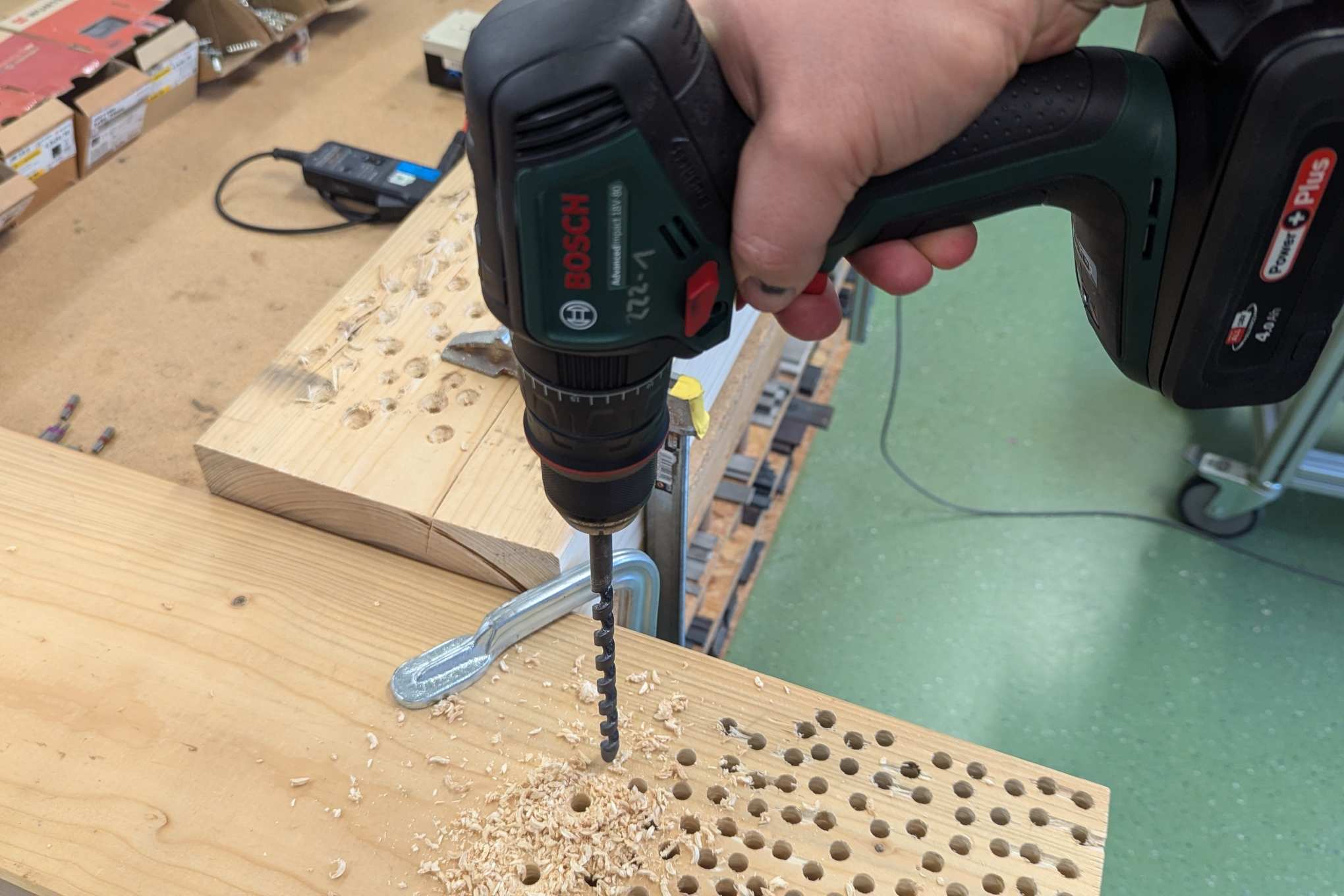 Henkilö poraamassa puuta testauslaboratoriossa.