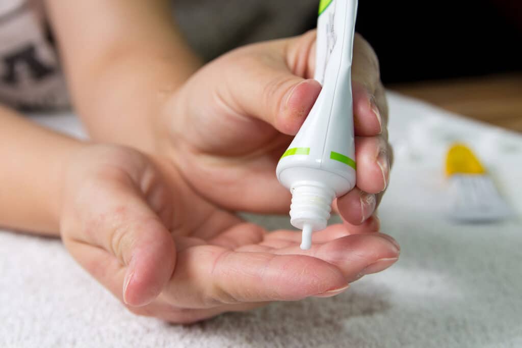 Henkilö pursottamassa voidetta käsiinsä.