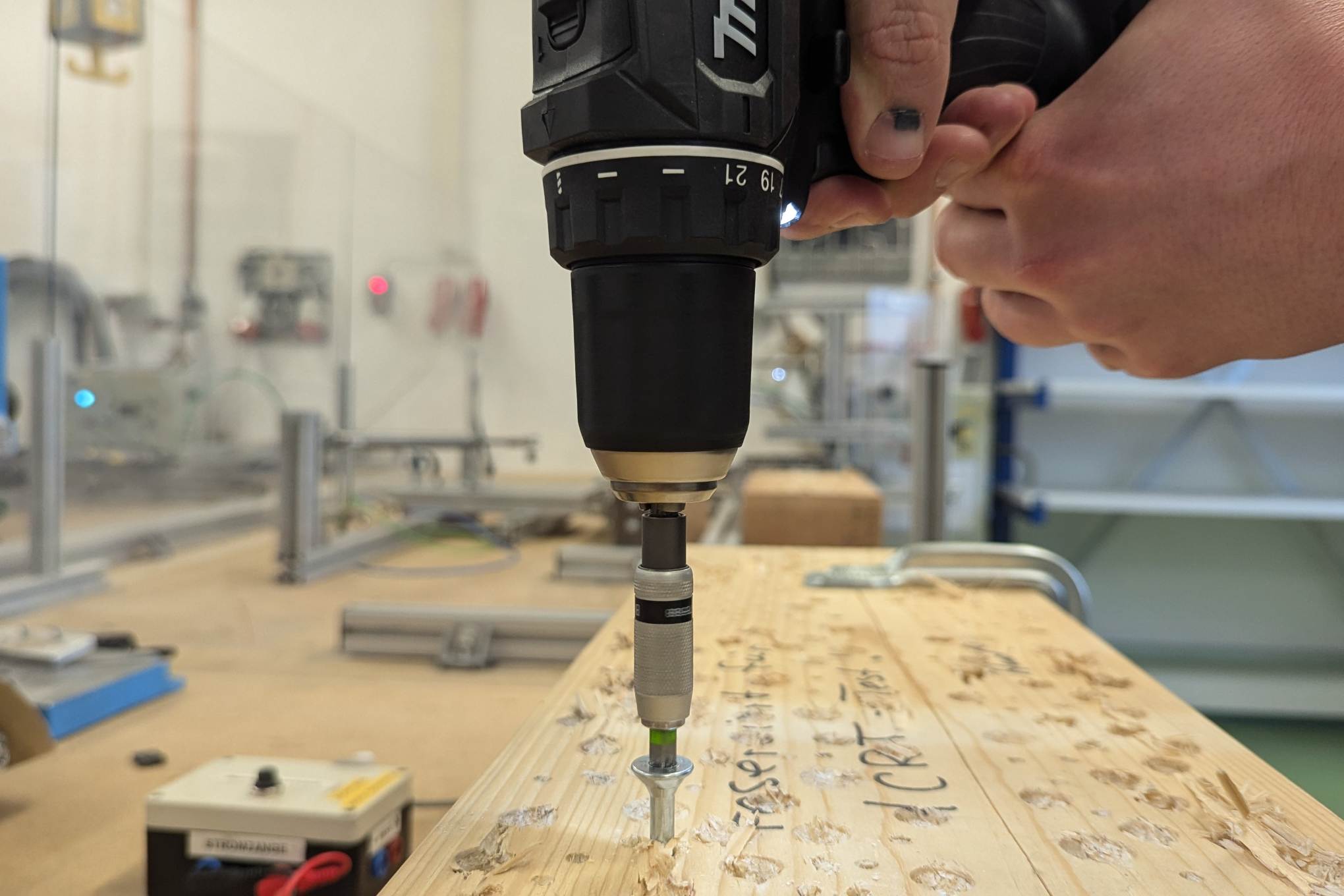 Henkilö poraamassa puuta testauslaboratoriossa.