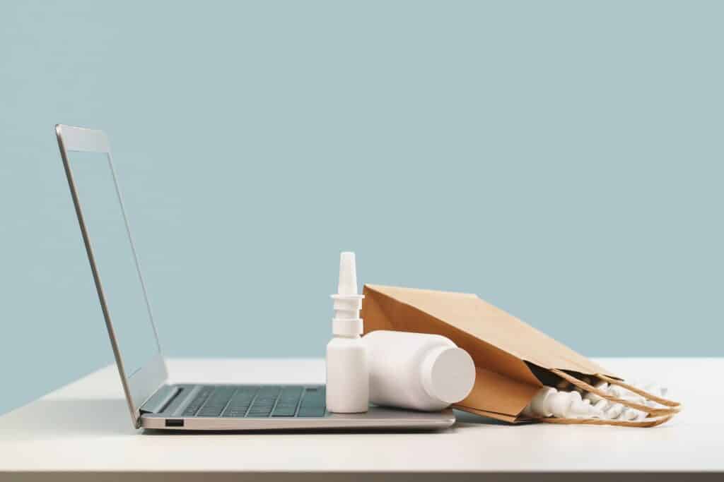 Pöydällä on tietokone ja lääkkeitä.