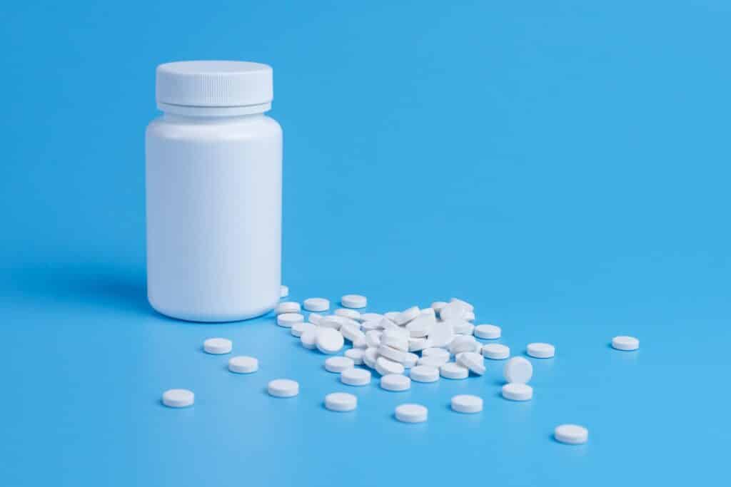 Vitamiinipurkki ja vitamiinitabletteja.