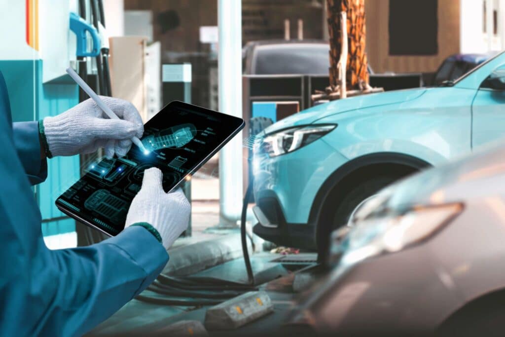 Sähköautoja, ja henkilö säätämässä auton asetuksia tabletilla.