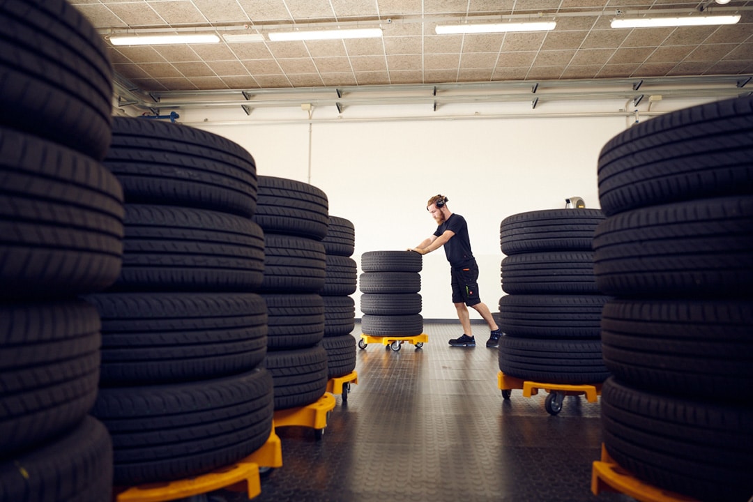 Useita rengaspinoja ja henkilö kuljettamassa renkaita.