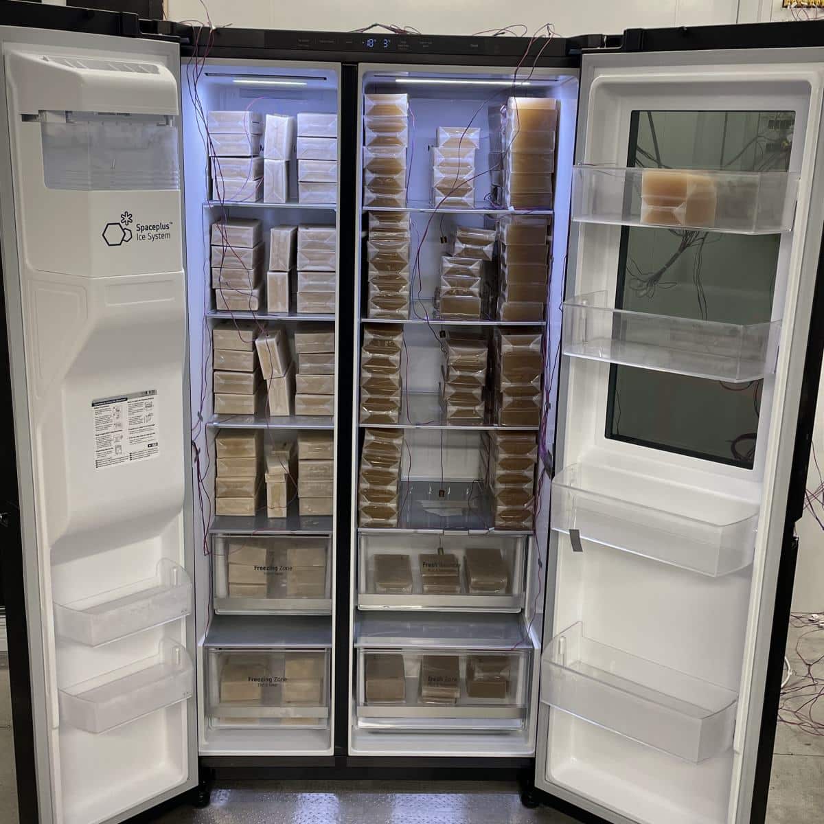 Elintarvikkeita simuloivia ruskeita pakkauksia ja lämpömittareita side-by-side-kylmälaitteen sisällä.