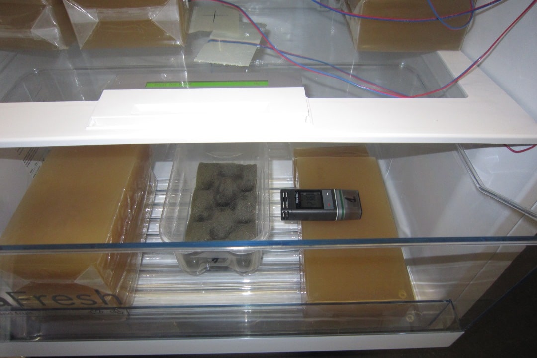 Elintarvikkeita simuloivia ruskeita pakkauksia ja ilmankosteusmittareita jääkaapissa.