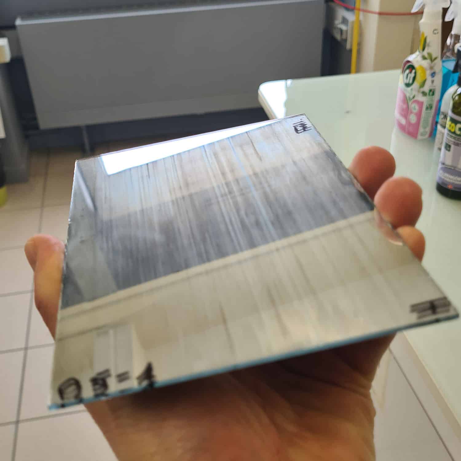 Henkilö pitää kädessään pientä peiliä. Taustalla näkyy yleispuhdistussuihkepulloja.