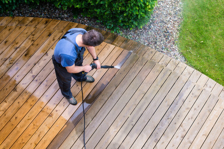 Henkilö pesee terassia painepesurilla.