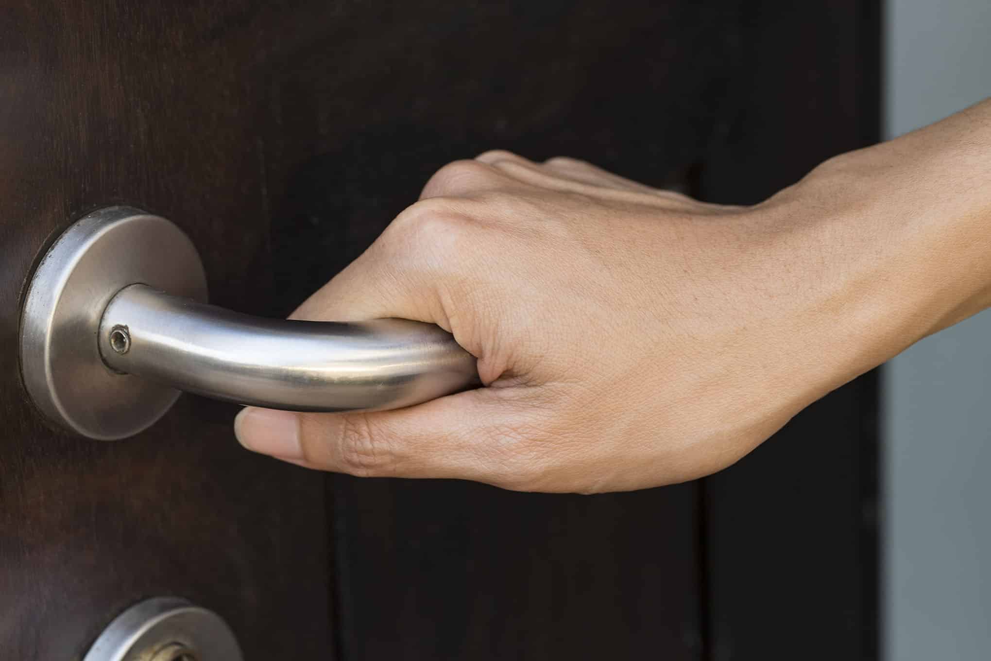 Henkilö painamassa oven kahvaa.