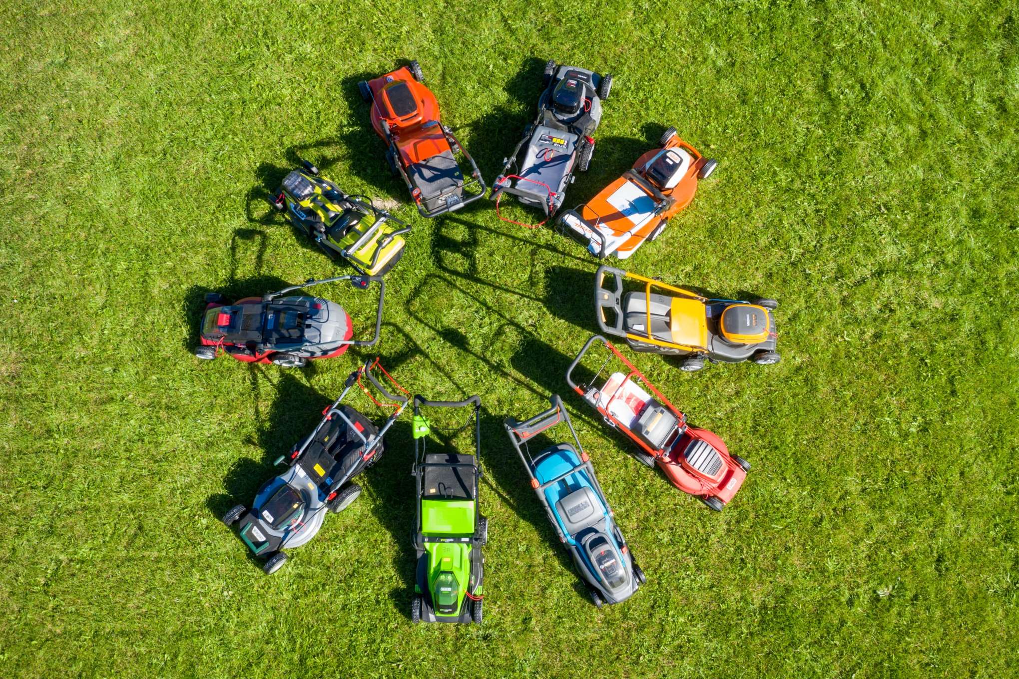 10 ruohonleikkuria, jotka ovat ringissä nurmikolla.