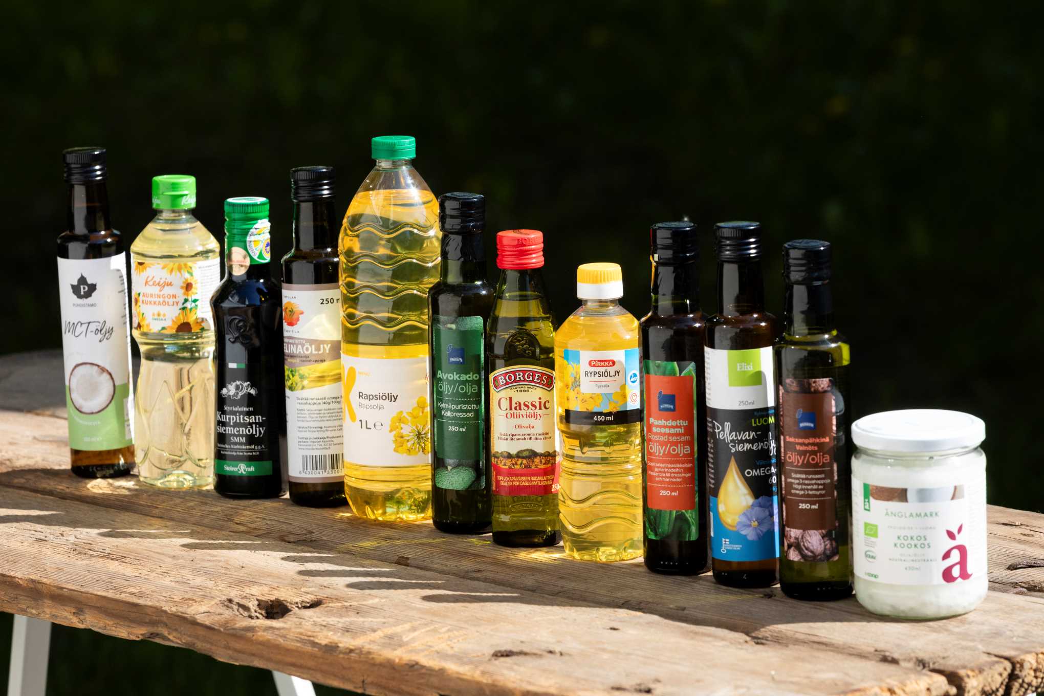Useiden eri valmistajien ruokaöljypulloja puupöydällä.