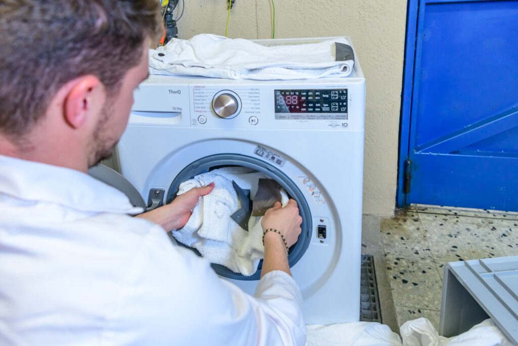 Henkilö ottamassa pyykkejä pesukoneesta.