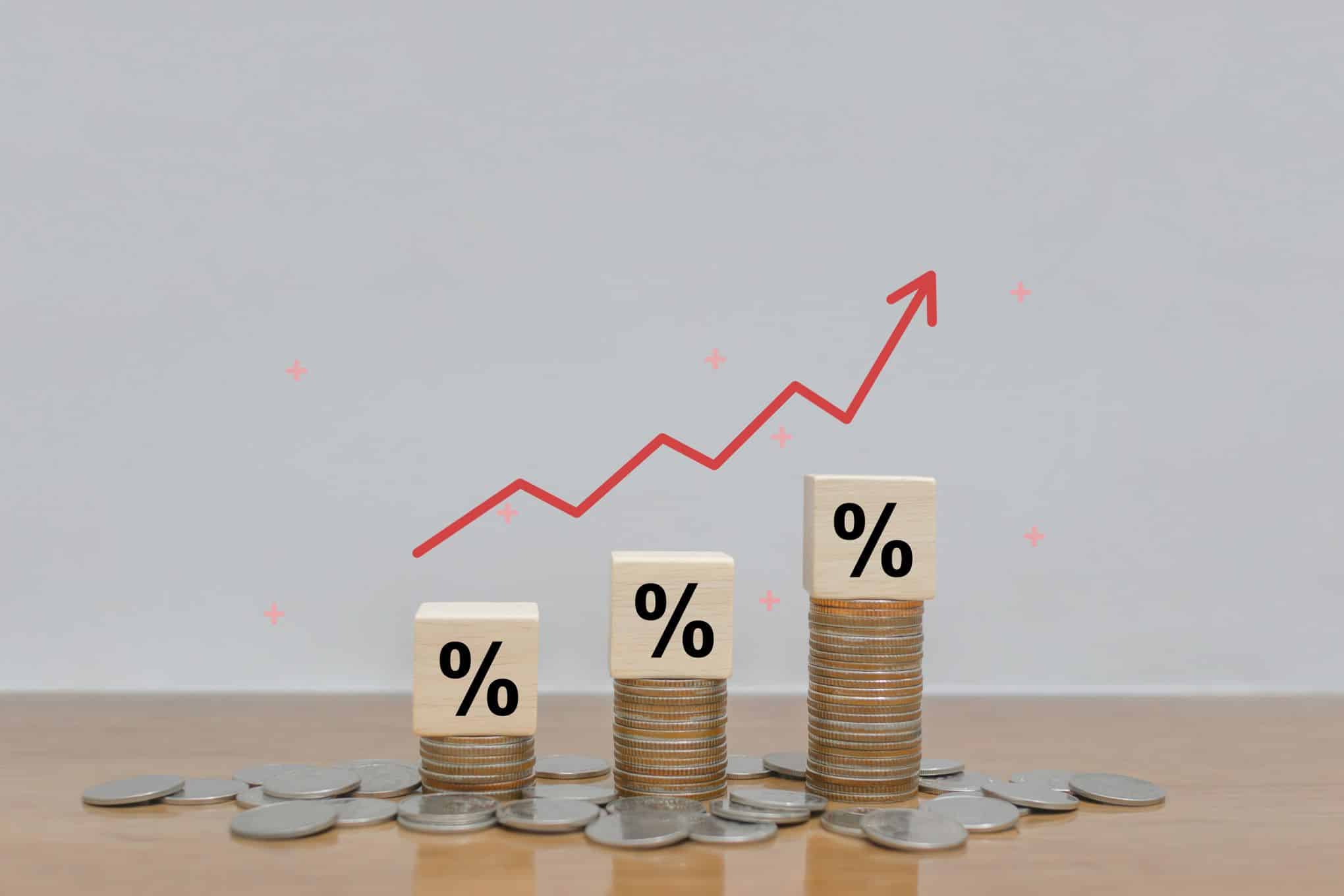 Pöydällä on kolikoita ja kolikkopinoja, joiden päällä on kuutioita, joissa on prosenttimerkki.