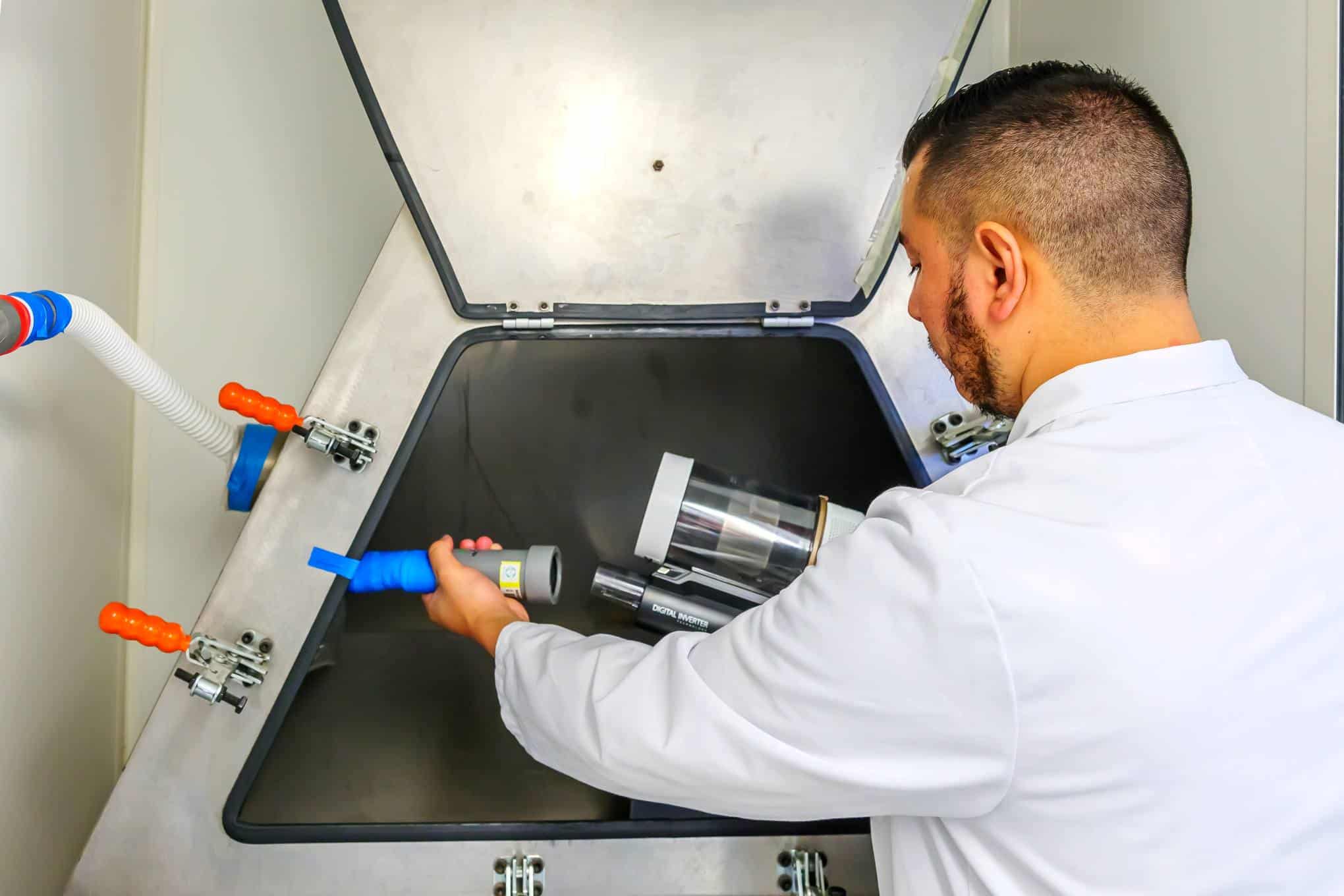 Testaajalla on käsissään varsi-imurin osia testasulaboratoriossa.