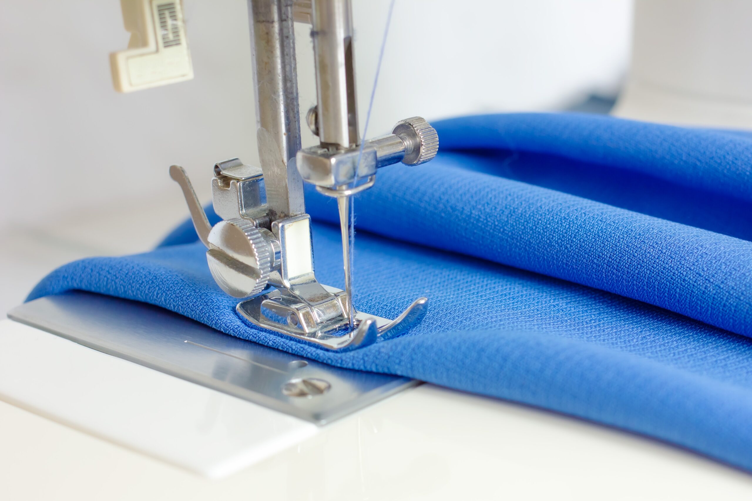 Ompelukone ja sinistä kangasta.